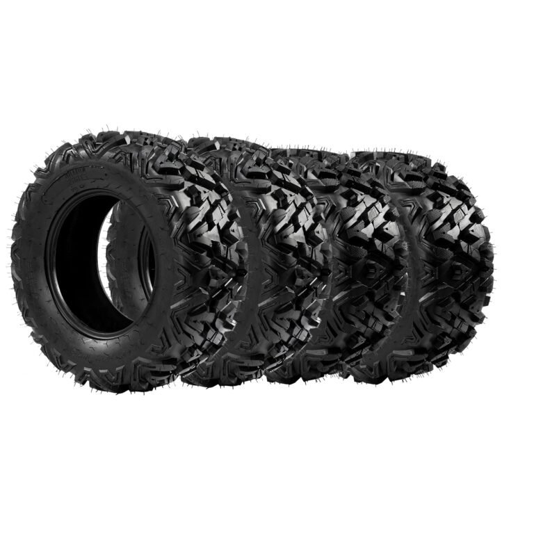 Four black, off-road tires with aggressive tread pattern, isolated on white background