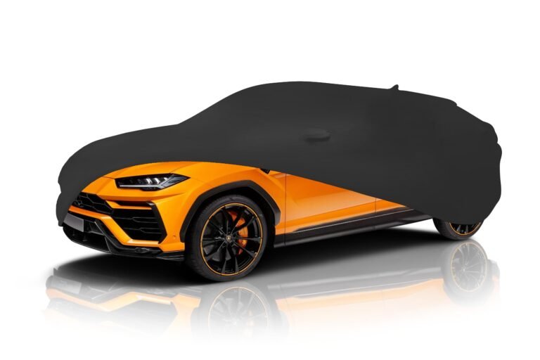 Orange Lamborghini SUV partially covered by a black car cover