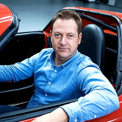 Man in blue shirt sitting in a red sports car